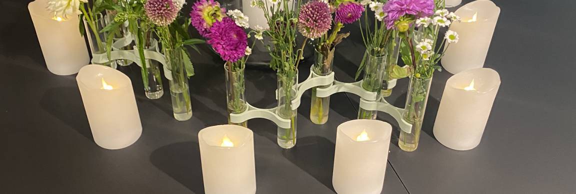 Kerzen aufgestellt im Kreis mit Blumenvasen in der Mitte